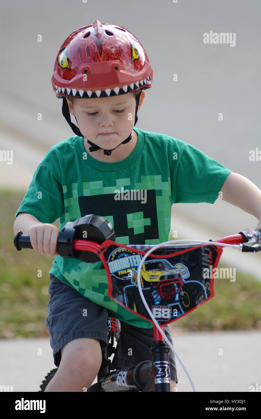 young boy riding his bike on the sidewalk close up Stock Photo