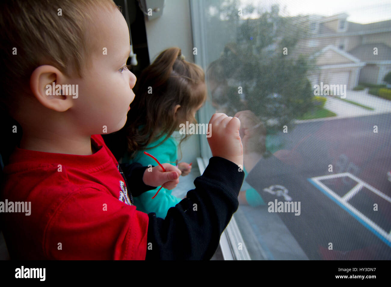 little girl and boy looking out window Stock Photo