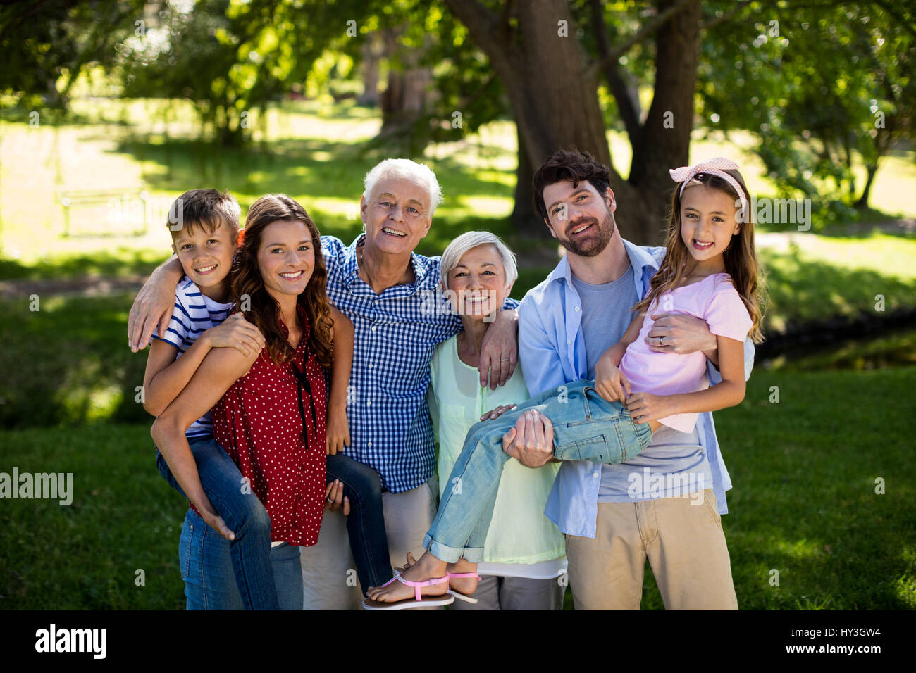 Portrait of smiling family posing together in park Stock Photo - Alamy