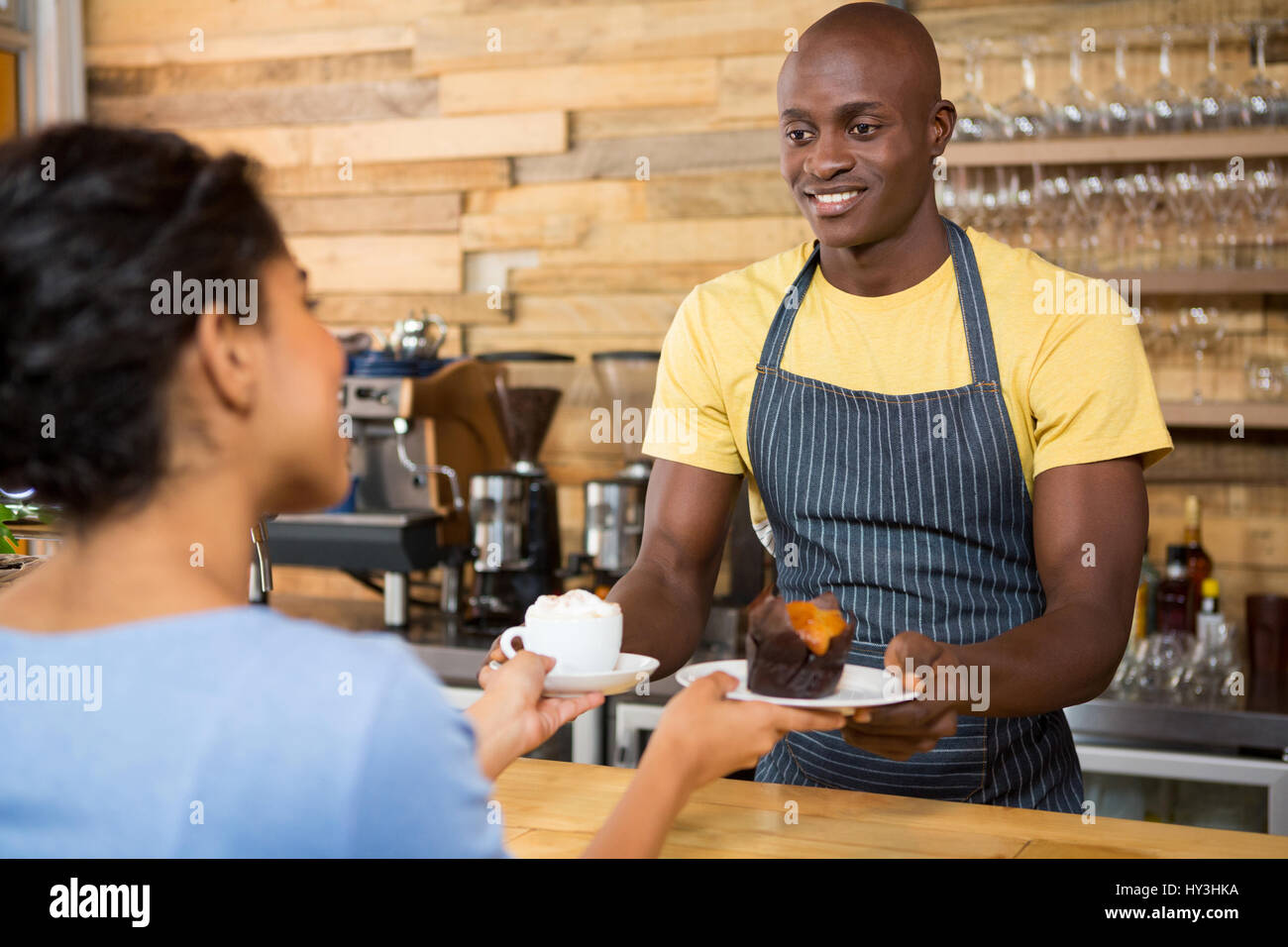 Portrait of male barista serving coffee and dessert to female customer
