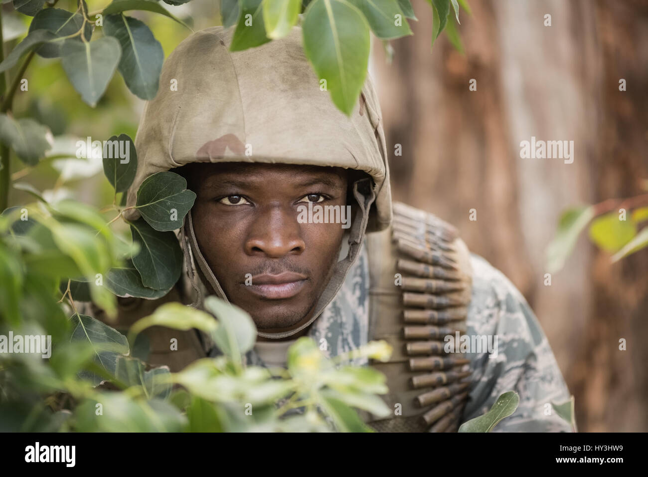 Military soldier hiding behind trees in boot camp Stock Photo