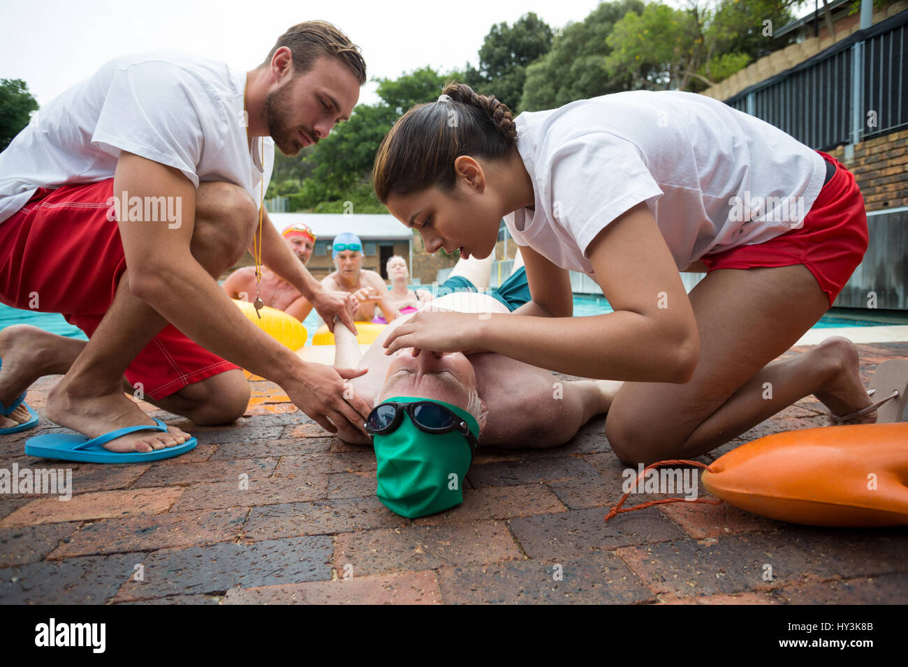 Male and female rescue workers helping unconscious senior man at poolside Stock Photo
