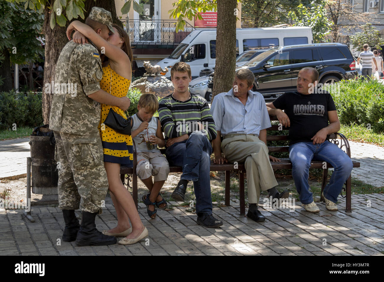 KIEV, UKRAINE - AUGUST 9, 2015: Ukrainian soldier on leave from the Eastern Ukraine conflict kissing his girlfriend next to his relatives  Picture of  Stock Photo