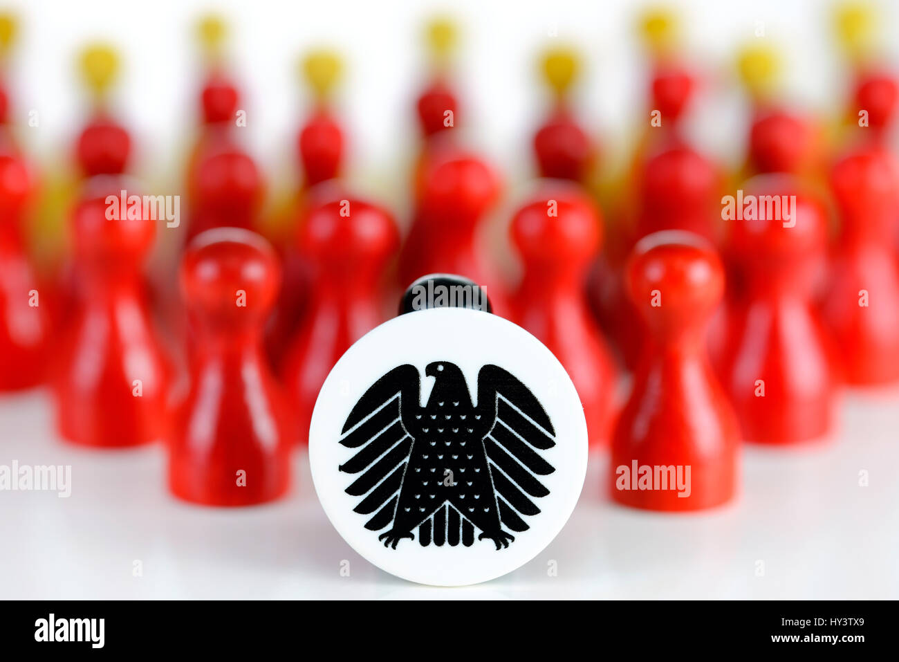 Black play figure with federal eagle before many red and yellow figures, Schwarze Spielfigur mit Bundesadler vor vielen roten und gelben Figuren Stock Photo