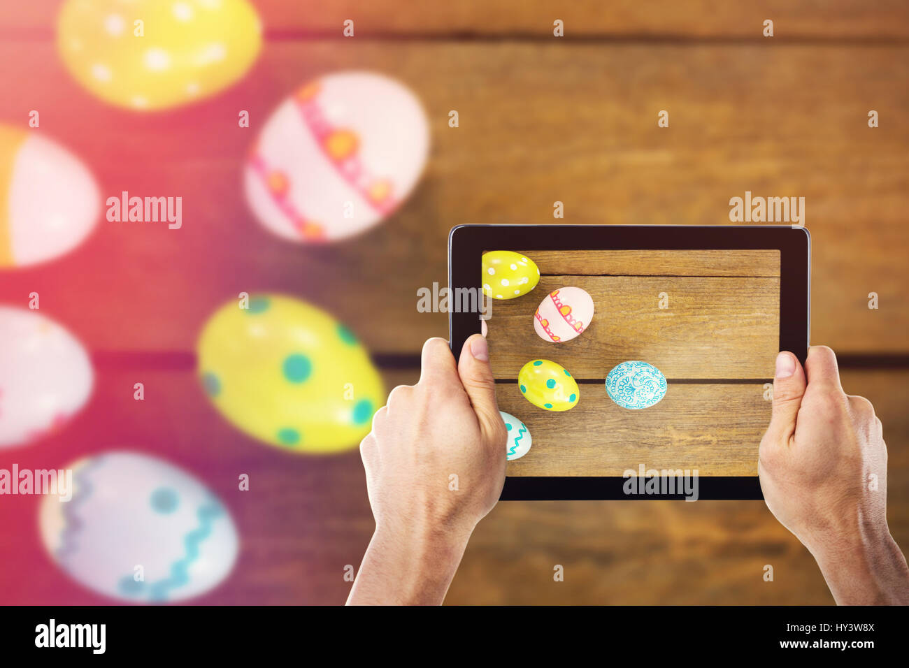 Cropped hand holding digital tablet against multicolored easter eggs Stock Photo