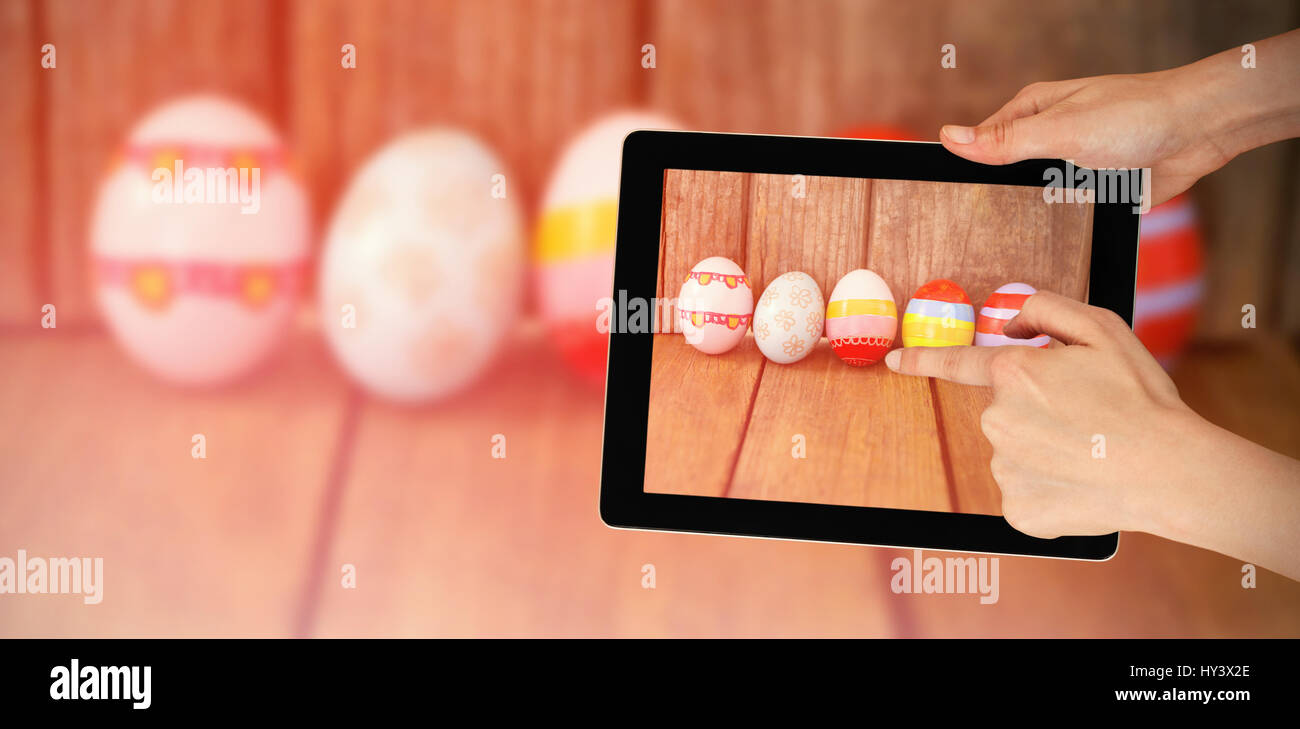 Hands touching digital tablet against white background against painted easter eggs arranged side by side Stock Photo