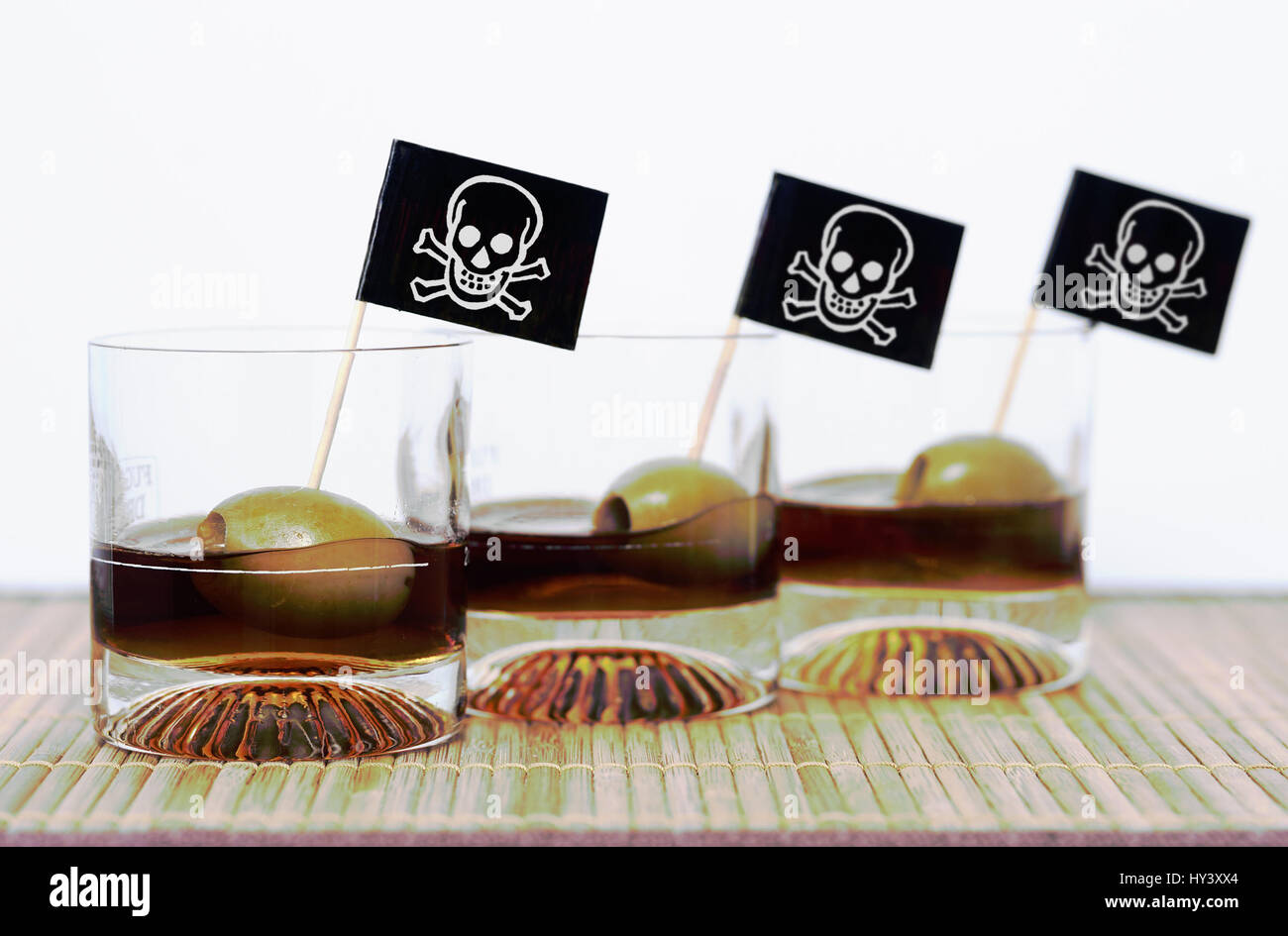 Three glasses with alcohol and death's-head flags, symbolic photo coma drinking, Drei Glaeser mit Alkohol und Totenkopf-Fahnen, Symbolfoto Komasaufen Stock Photo