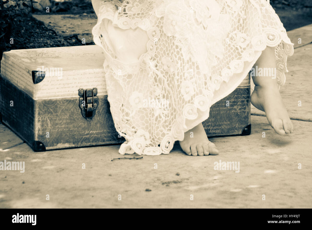 No face just chunky toes of a toddler girl with lacey dress and tinted luggage Stock Photo