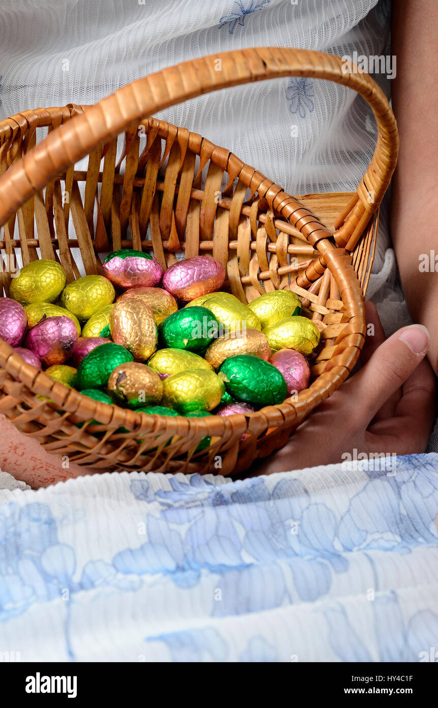 Child's hand holding easter egg basket and blue and white dress Stock Photo