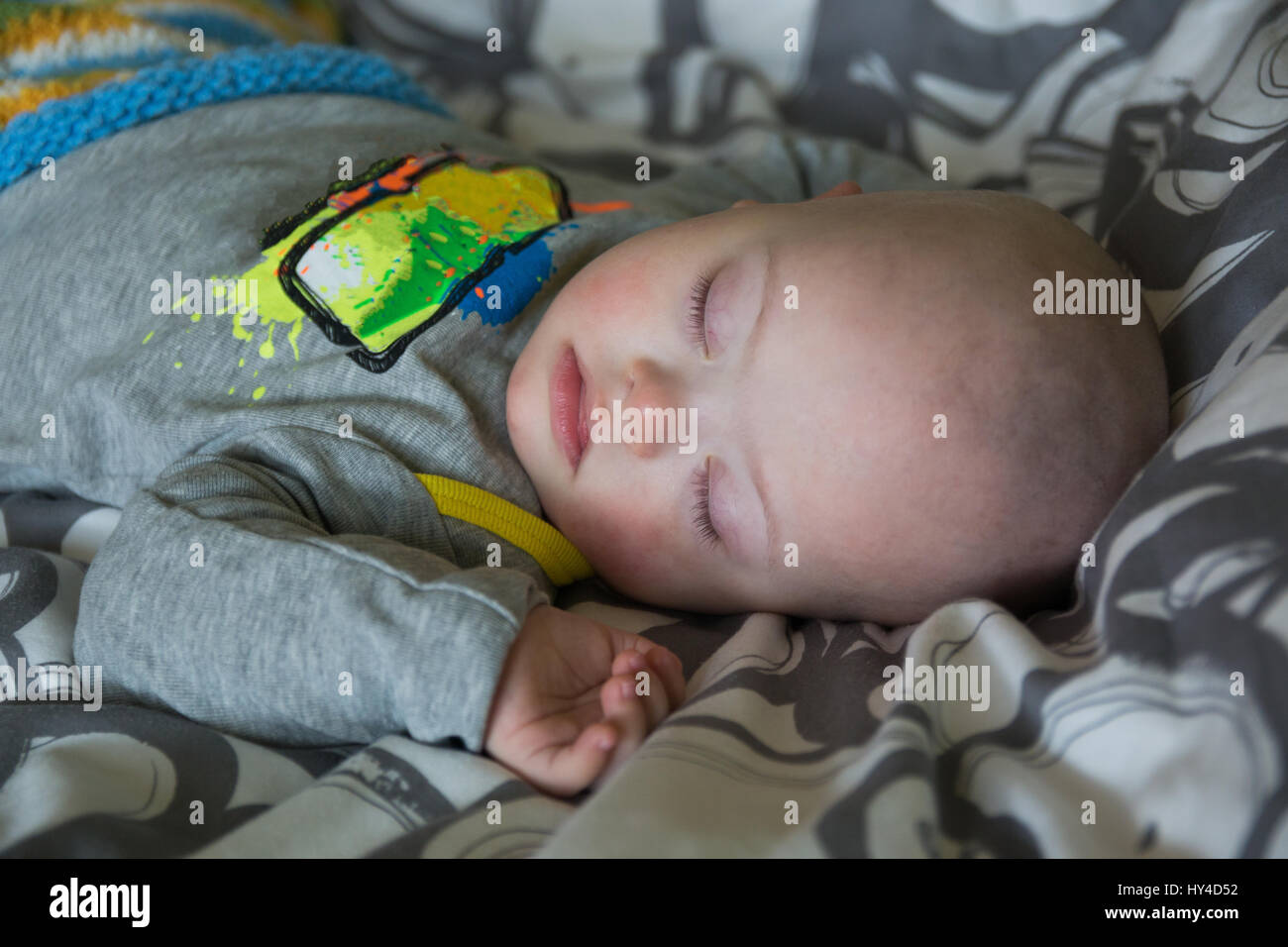 Cute baby boy with Down syndrome sleeping on the bed in home bedroom