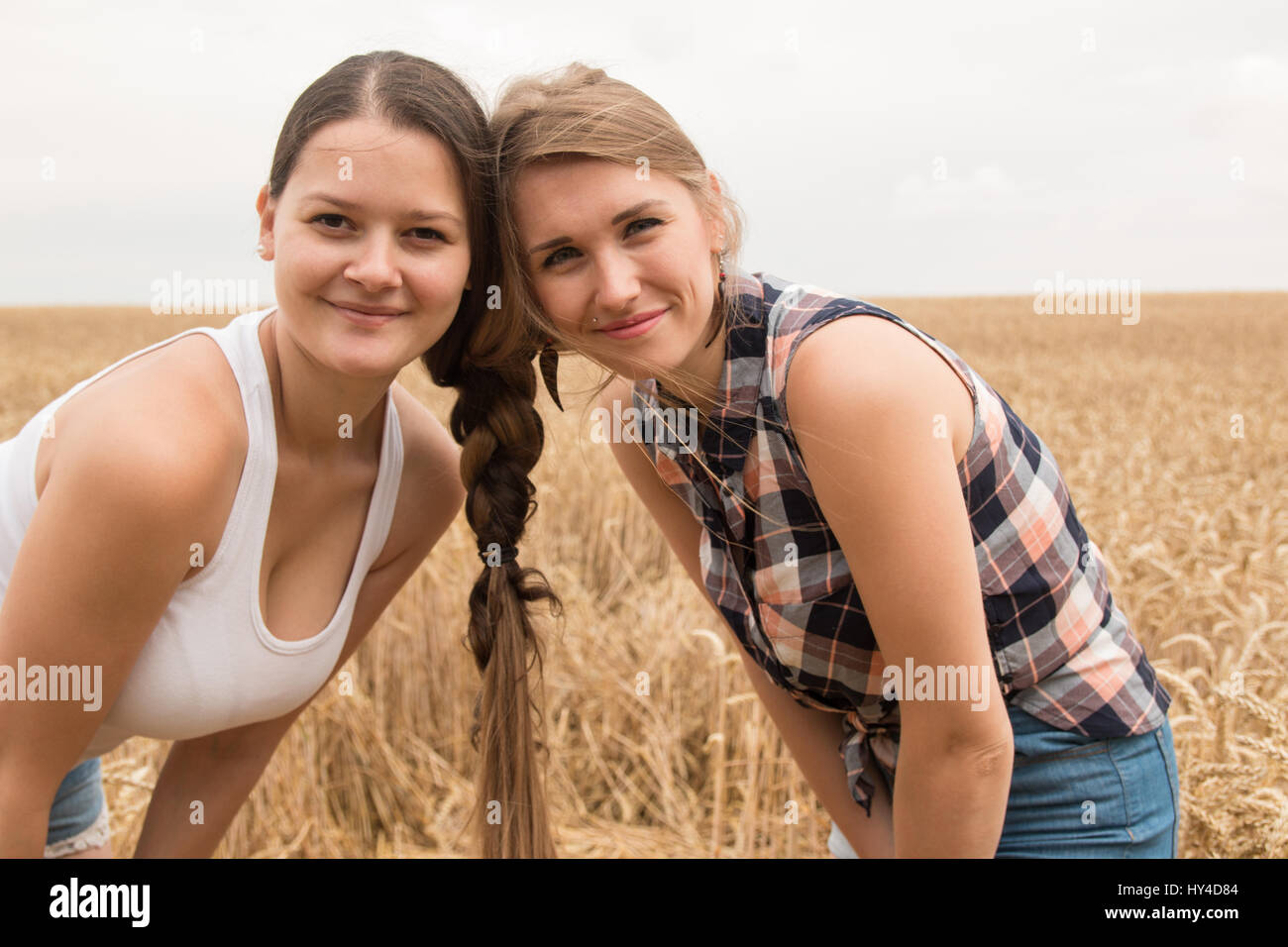 Two girls is best friends with hair braided together in a wheat field