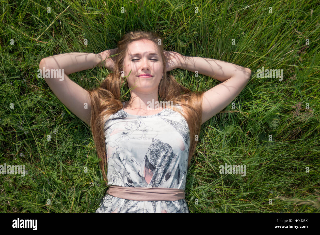 Portrait of a young girl lying down on grass in the park Stock Photo ...