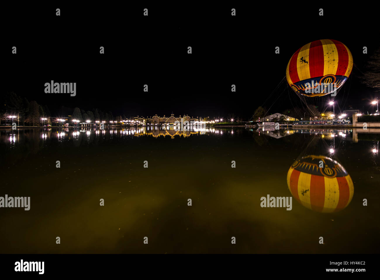 Newport Bay Club hotel at night across Lake Disney in the Disney Resort in Marne-la-Vallée Paris, France and Panoramagique balloon with reflection Stock Photo