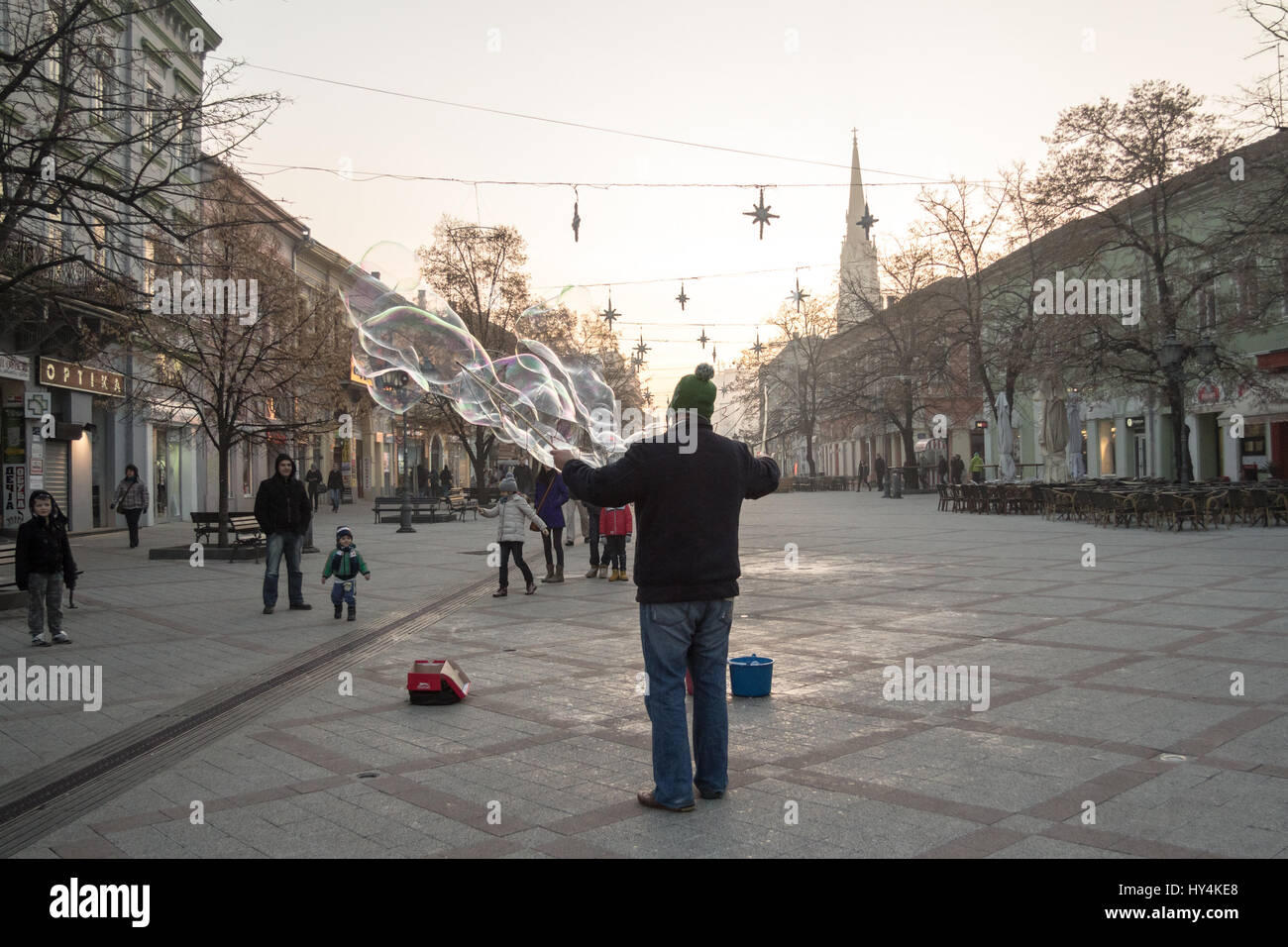 NOVI SAD, SERBIA - DECEMBER 13, 2015: Street performer making soap bubbles in order to amuse people passing by pn Novi Sad main street, Zmaj Jovina  S Stock Photo