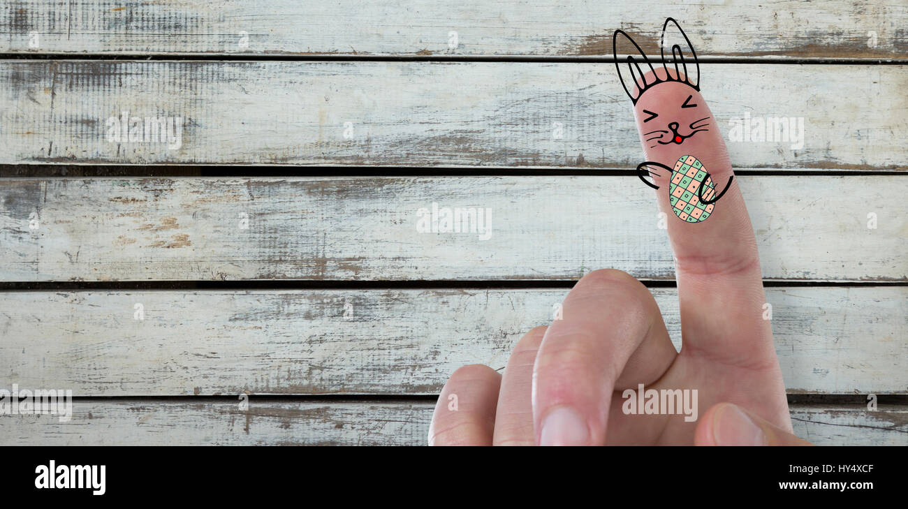 Digitally composite image of fingers representing Easter bunny  against wood background Stock Photo