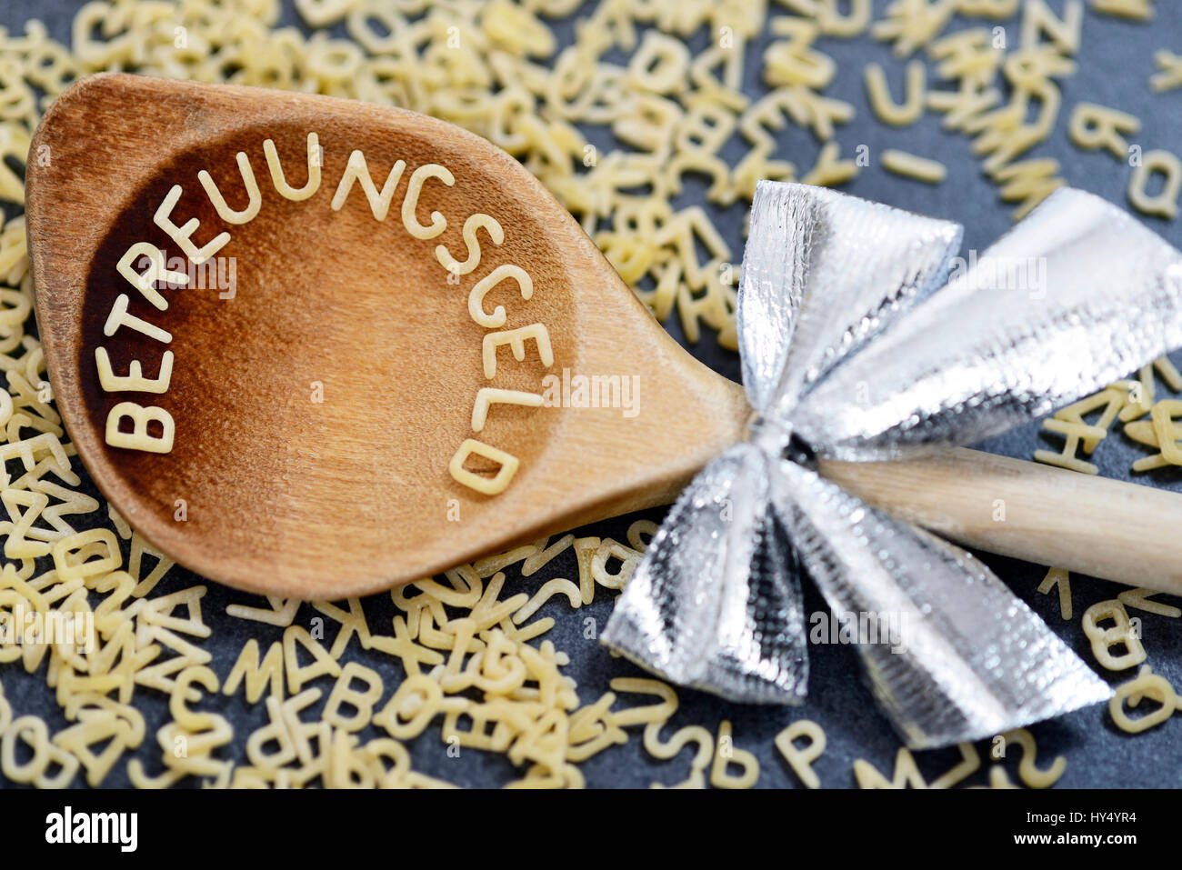 Cooking spoon with care money stroke from noodle letter, Kochloeffel mit Betreuungsgeld-Schriftzug aus Nudelbuchstaben Stock Photo