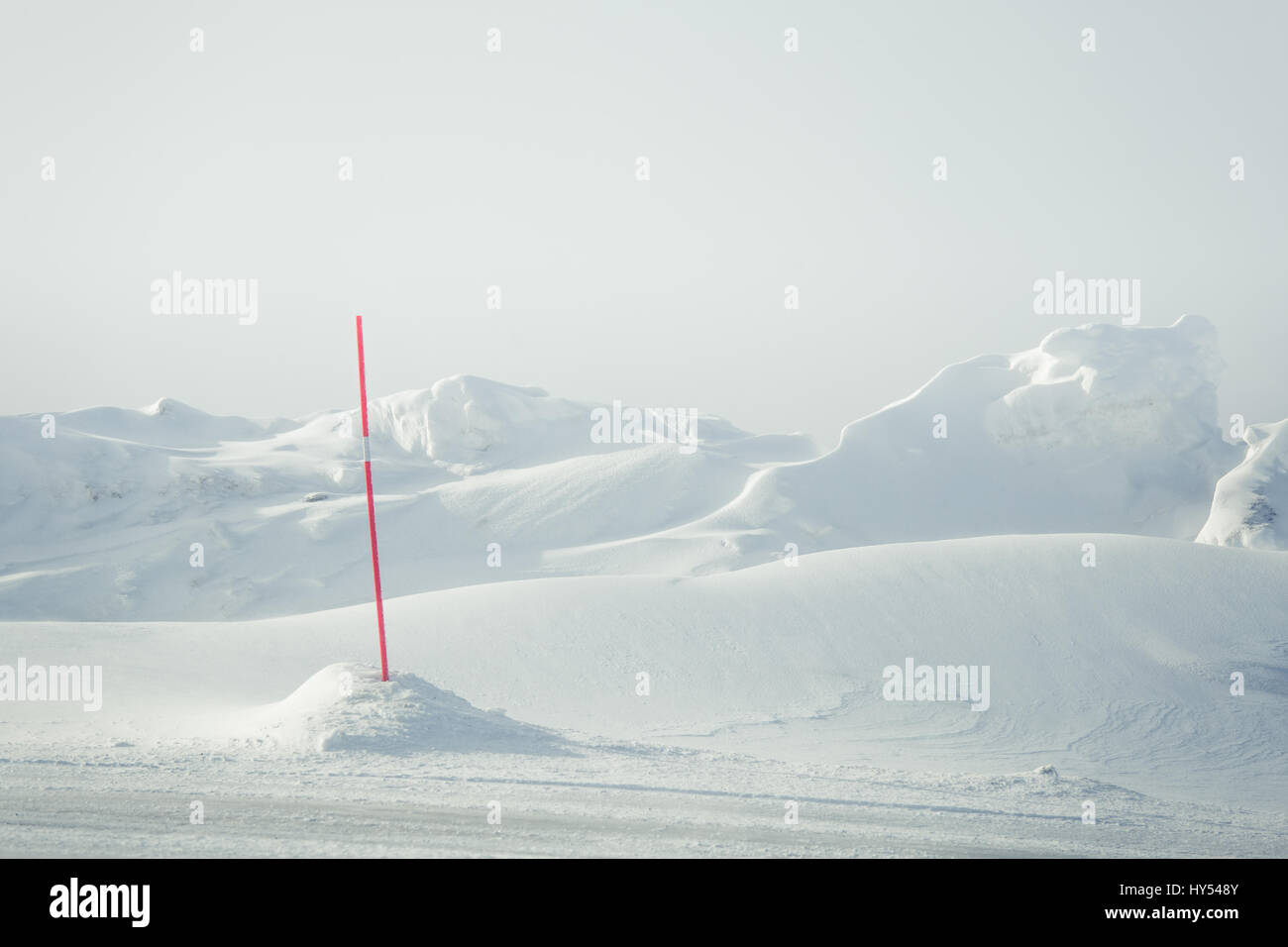 A beautiful landscape with a white, snowy road with safety poles in the Norwegian winter Stock Photo