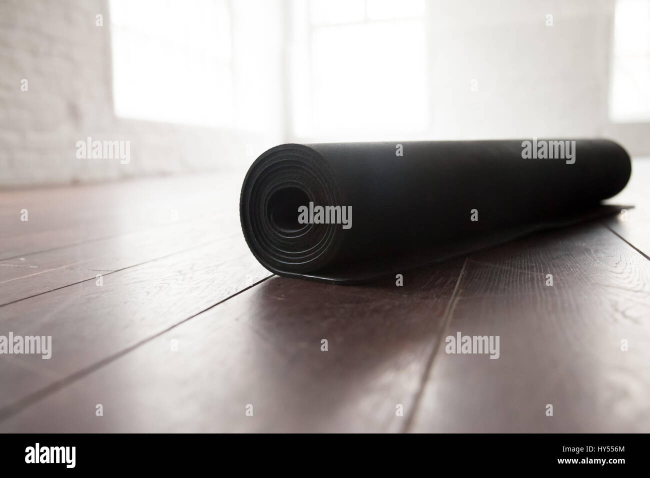 Rolled up yoga or pilates mat for exercise on natural wooden floor, sport class before or after