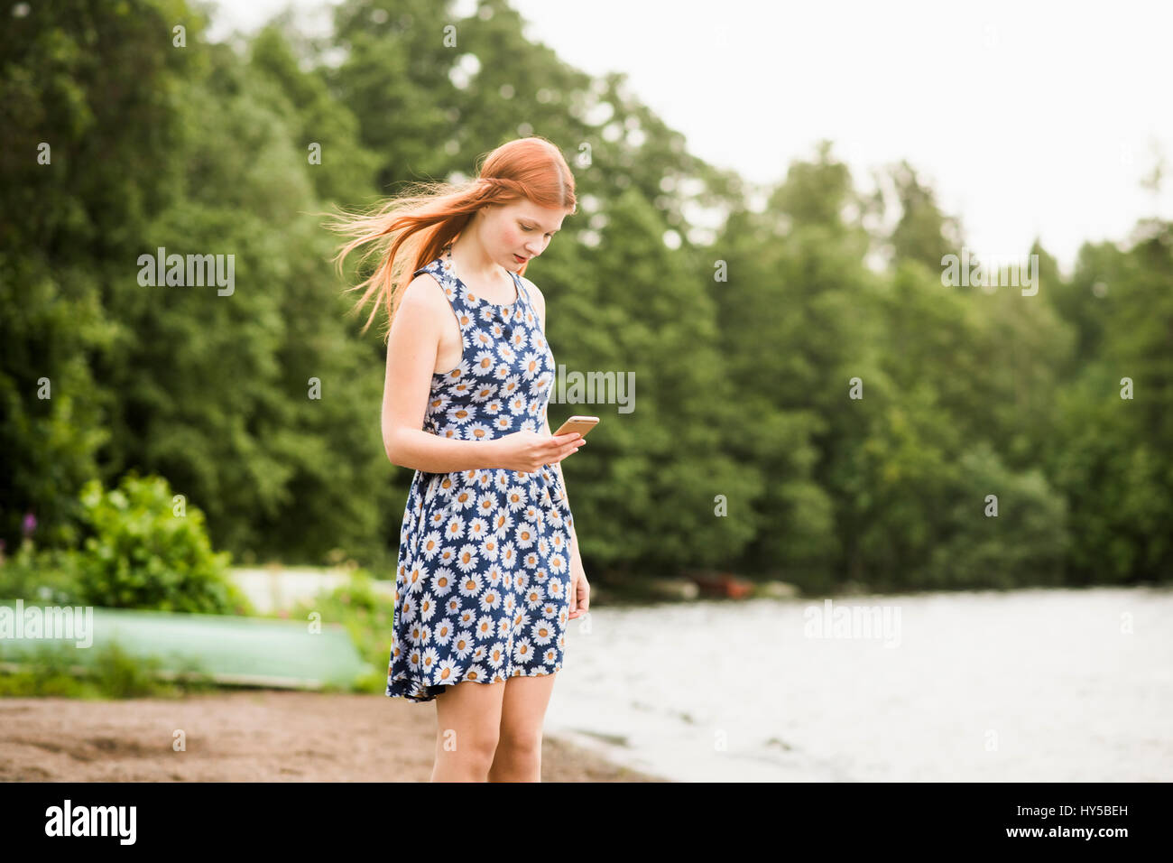 Finland, Pirkanmaa, Tampere, Woman with mobile phone standing on beach Stock Photo