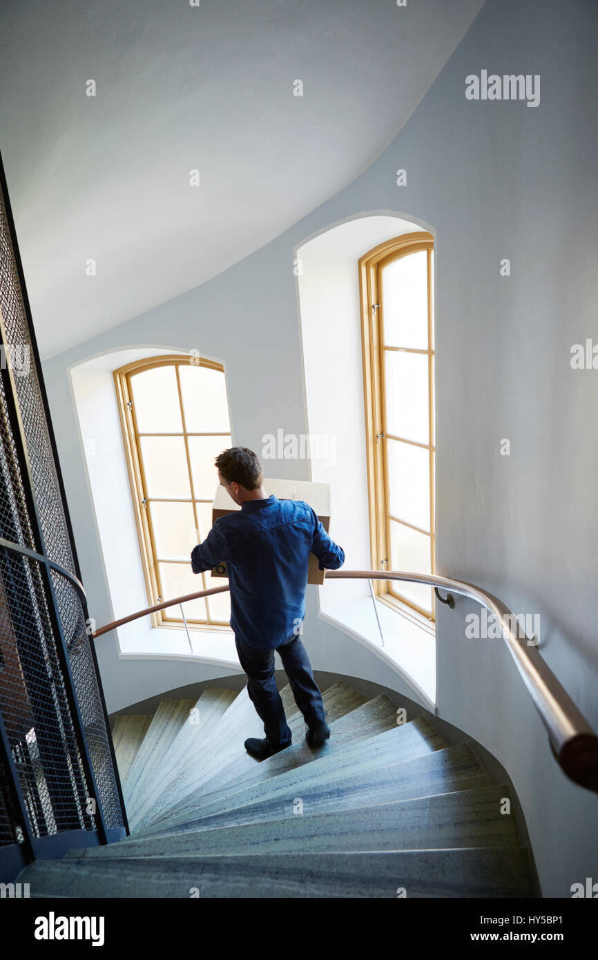 Sweden, Man walking on steps, carrying box Stock Photo