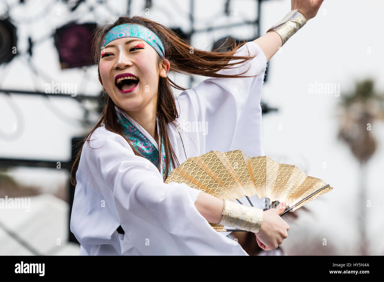 Japan, Kumamoto, Hinokuni Yosakoi dance Festival. Close-up of woman dancer in white yukata and blue head-band, holding open fan, swirling around. Stock Photo