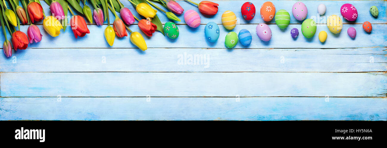 Easter Eggs And Tulips On Blue Wooden Plank Stock Photo
