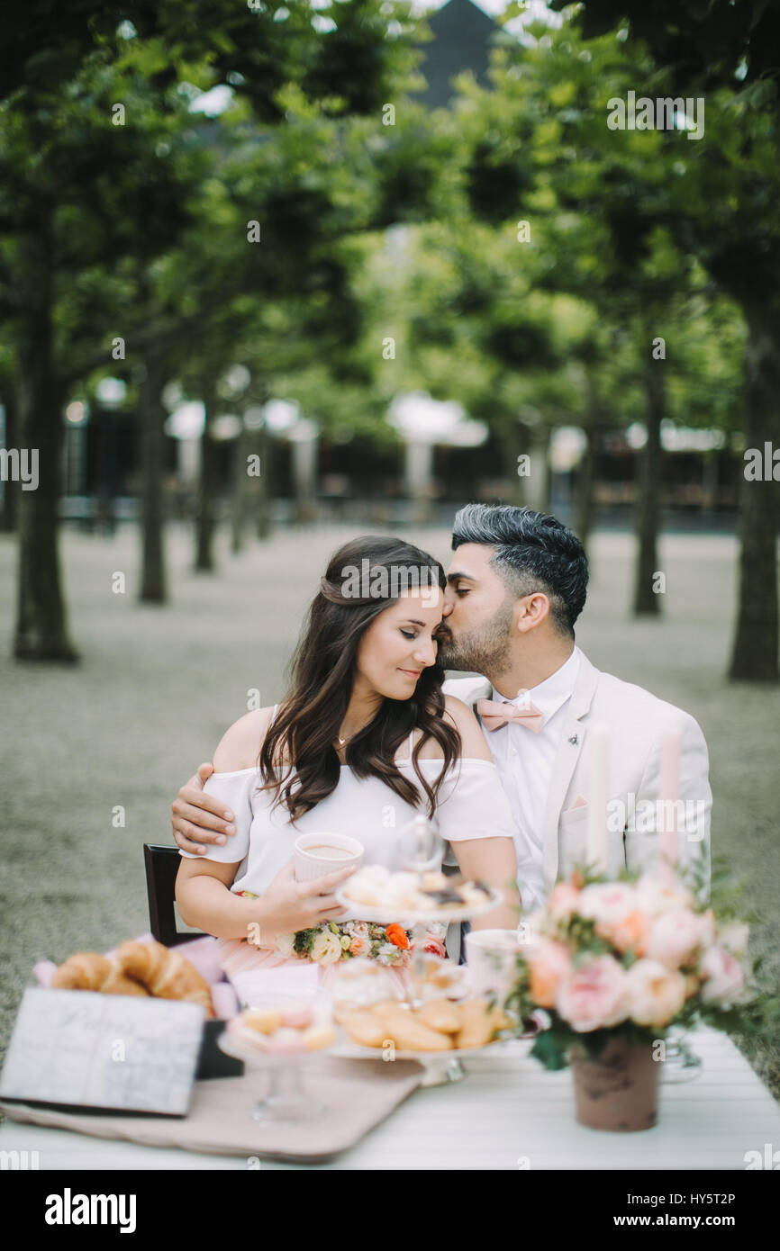 Young couple sitting at table, in love, happy, kiss, smiling Stock Photo