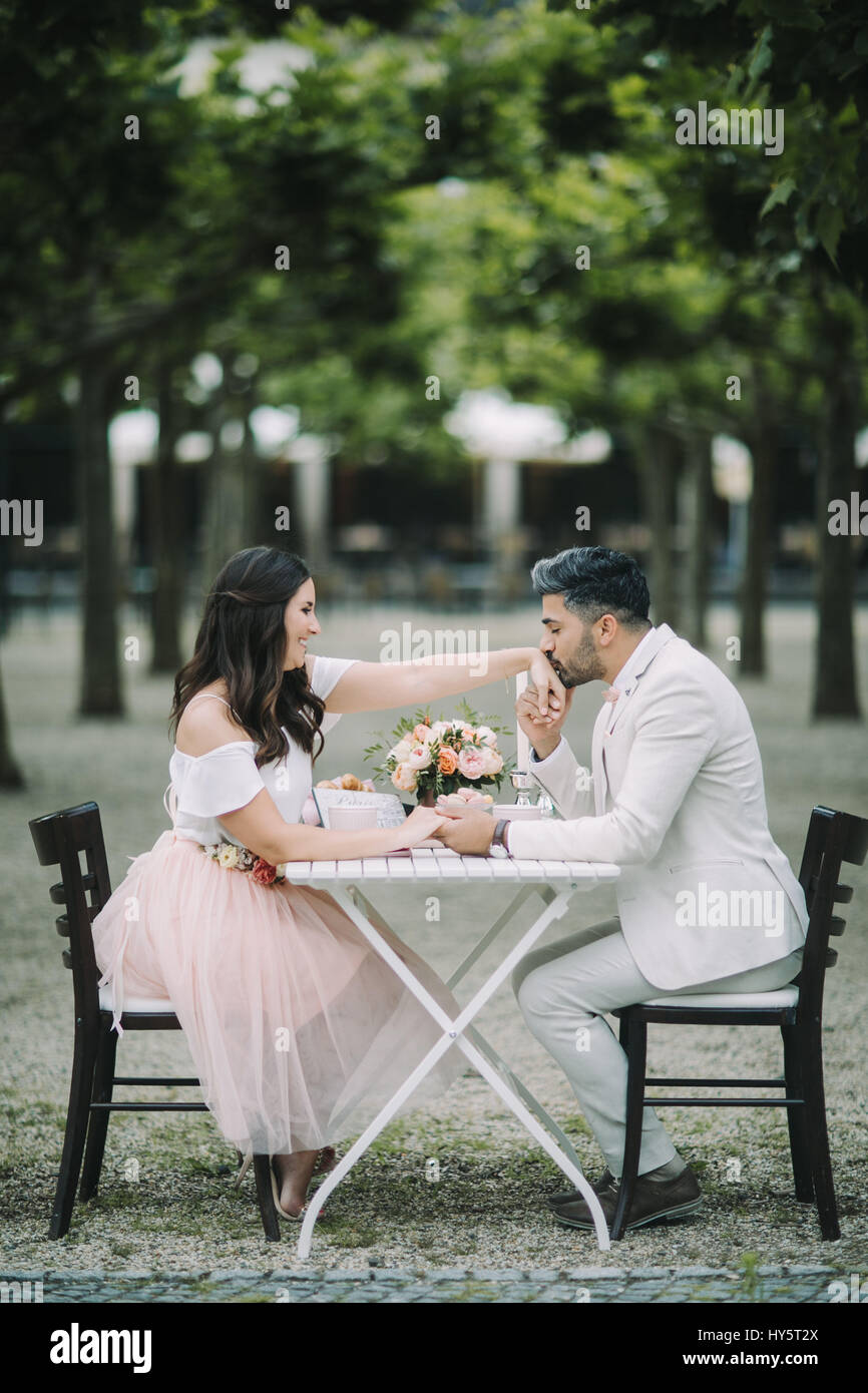 Young couple sitting at table, in love, happy, holding hand, handcuff, Stock Photo