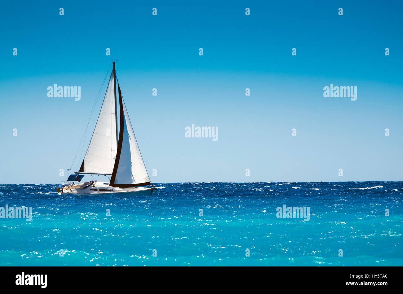 White boat sailing in the open blue sea in Greece Stock Photo