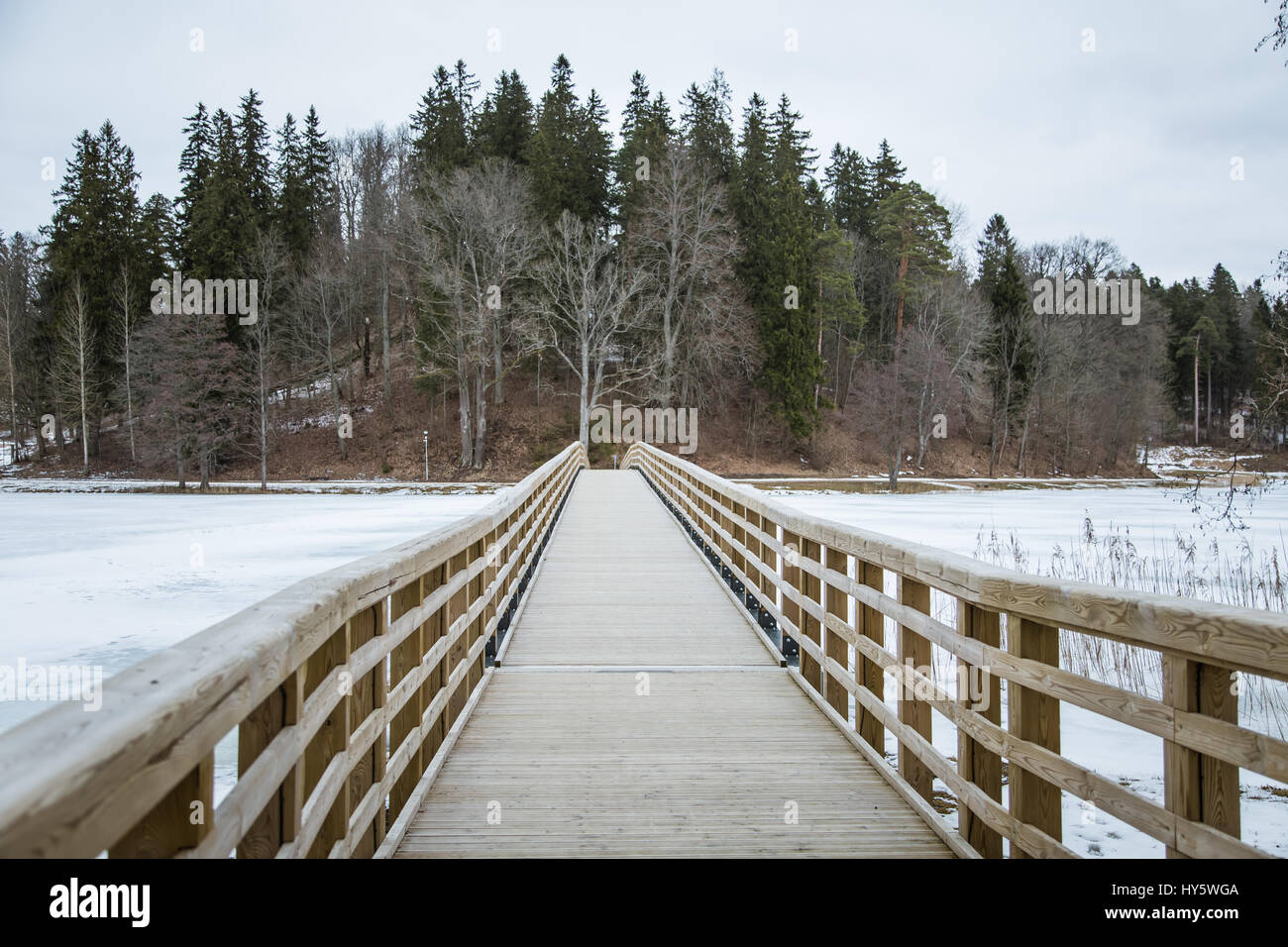 A beautiful wooden bridge over the frozen river Stock Photo - Alamy