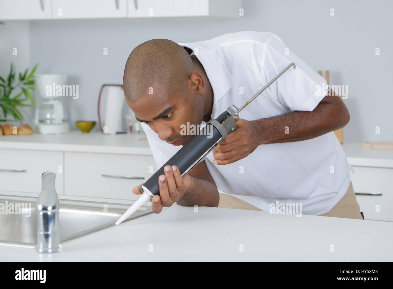 Man sealing around kitchen sink Stock Photo Alamy