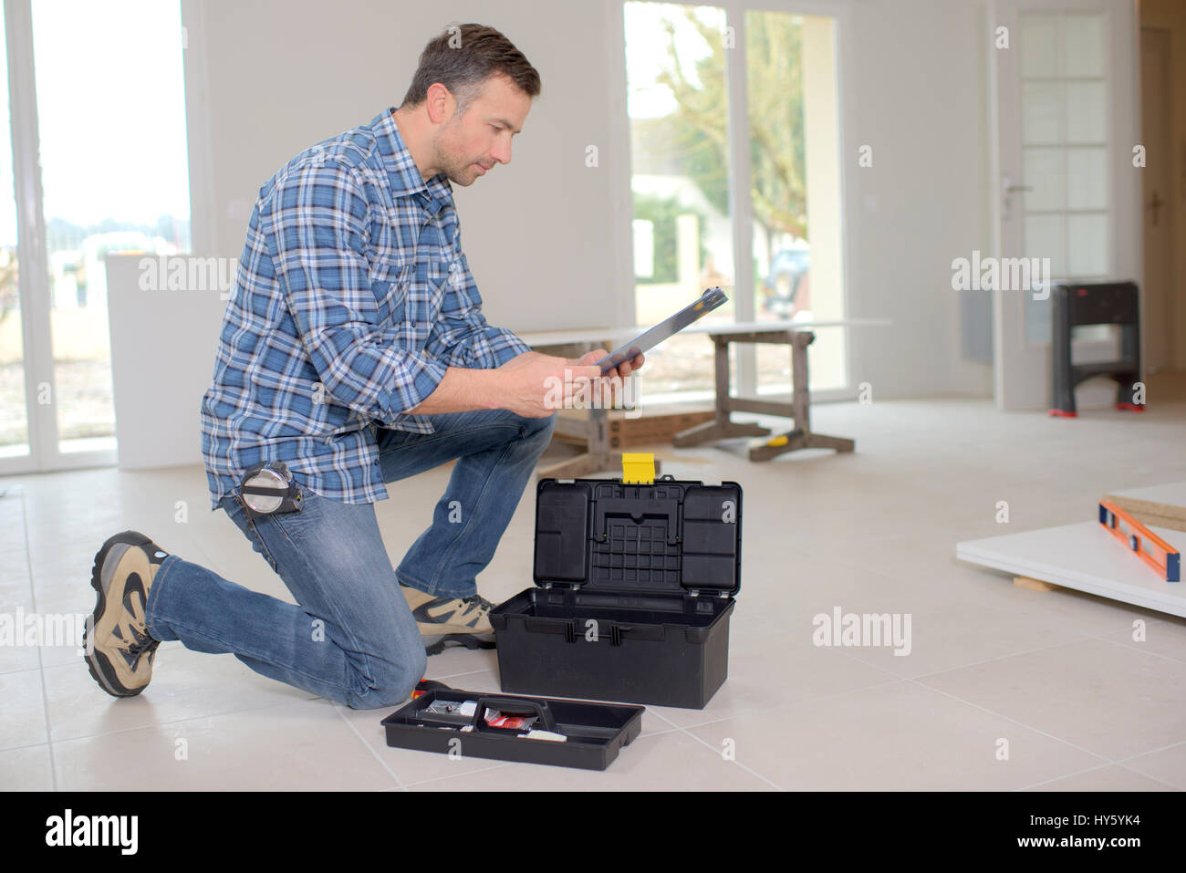 Builder kneeling by his toolbox Stock Photo - Alamy