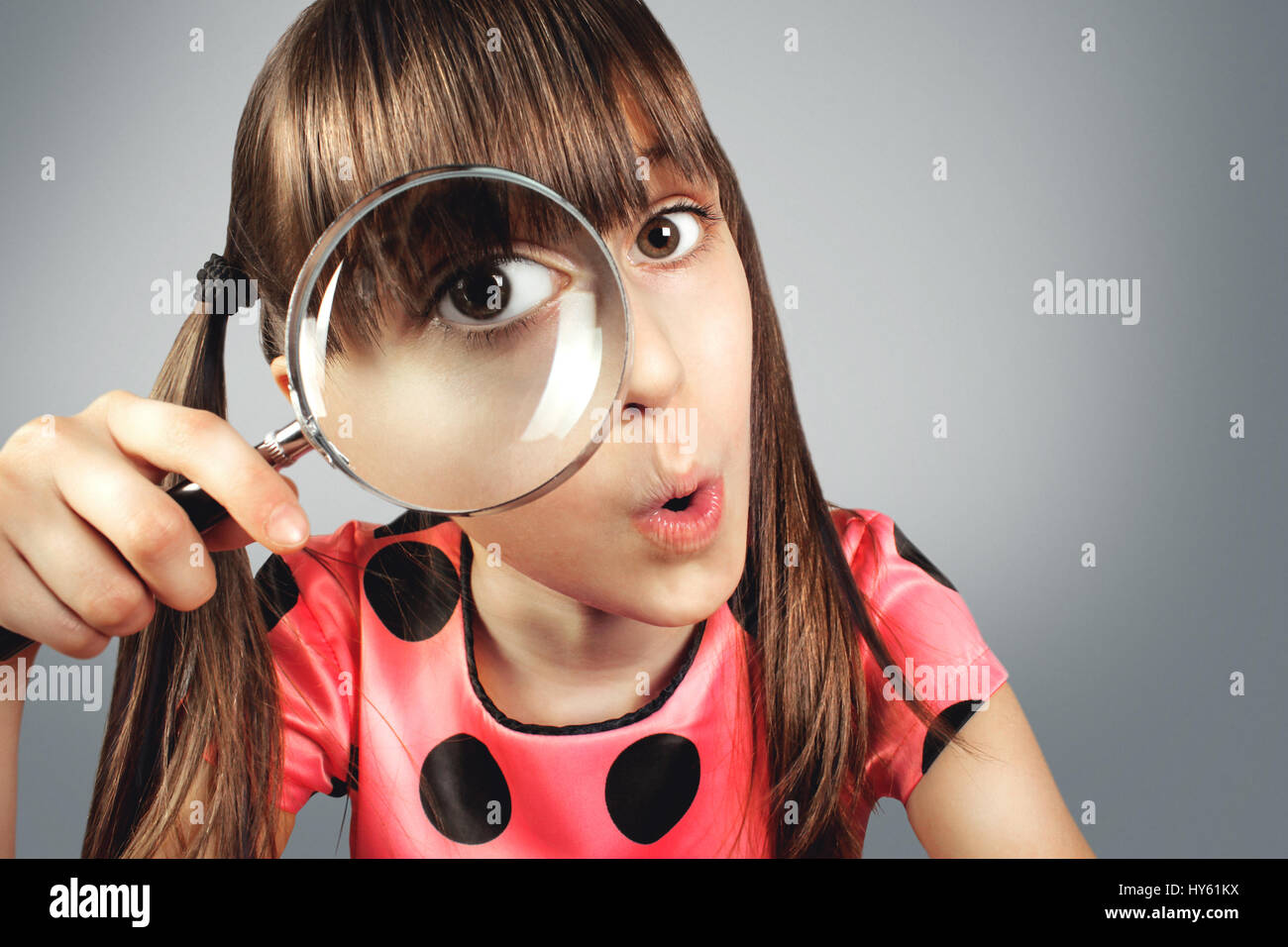 amazed child girl looking through magnifying glass, searching concept Stock Photo