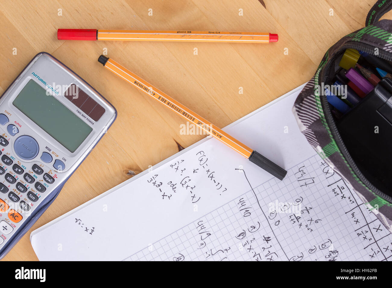 An exercise book on a desk with pens and a calculator Stock Photo - Alamy