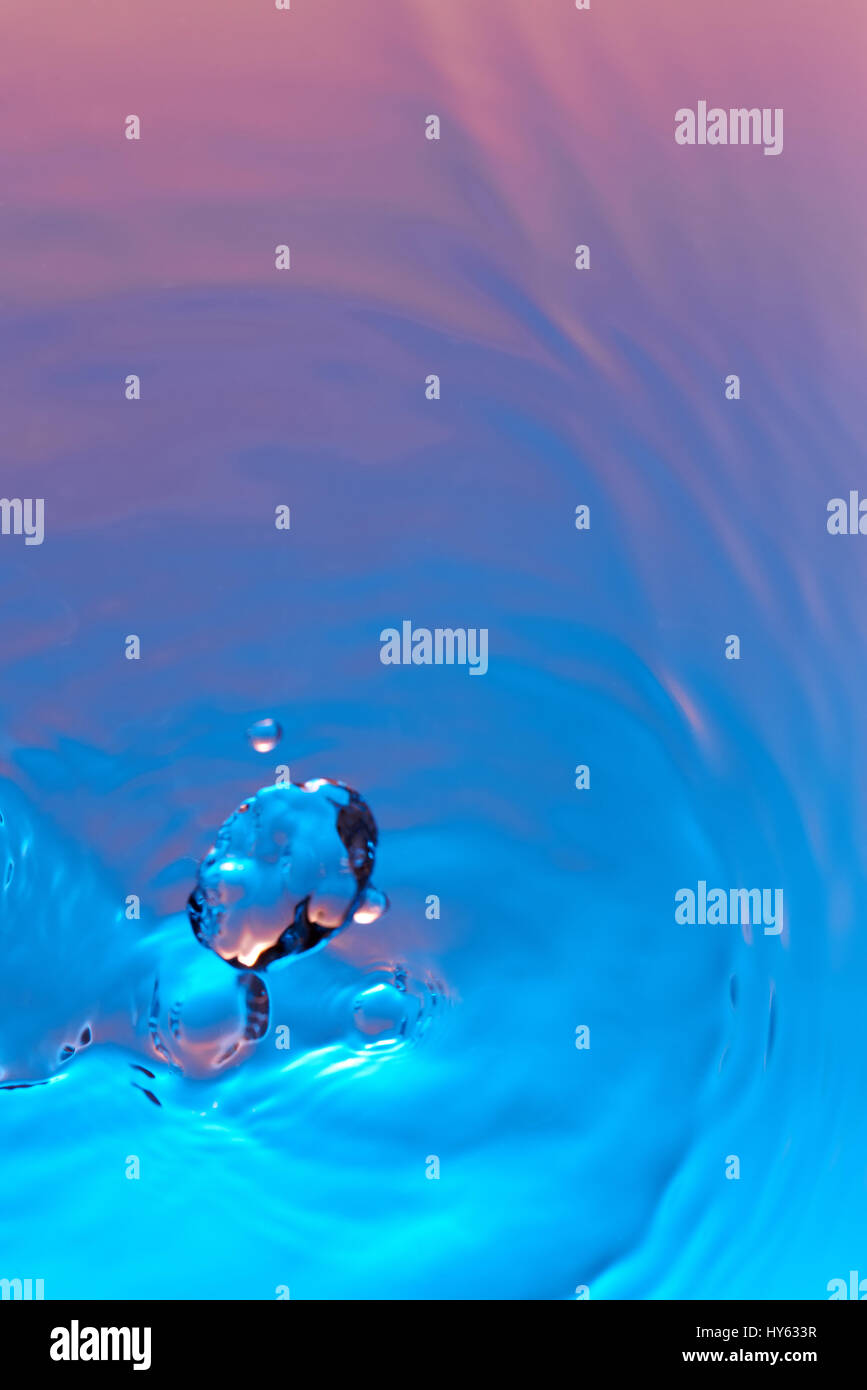Drop fall in colorful pink water background closeup Stock Photo - Alamy