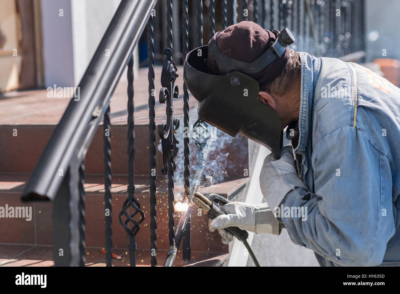 A worker welding metal handrails on the stairs. Wrought iron railings. Private house. Ukraine