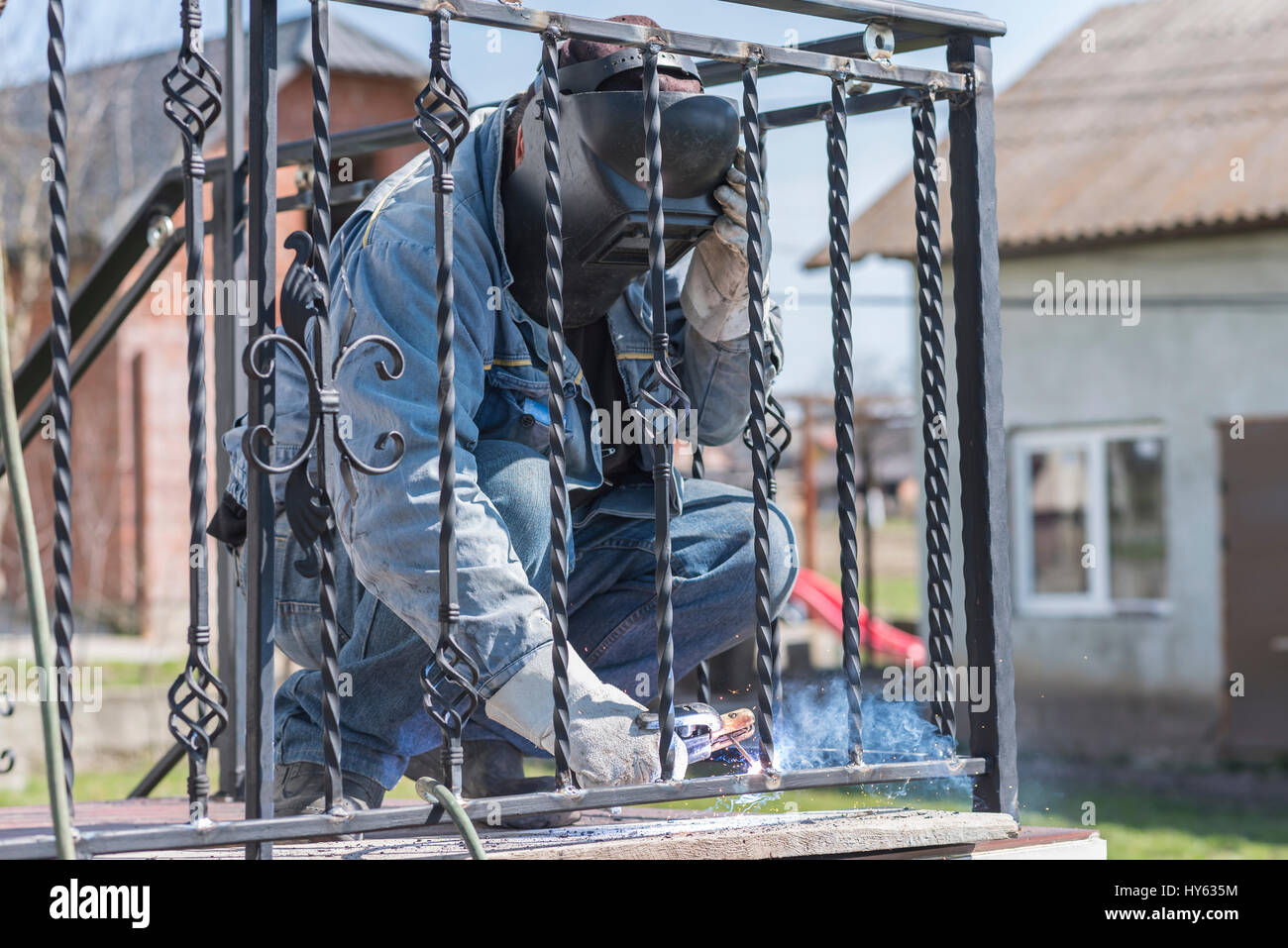 A worker welding metal handrails on the stairs. Wrought iron railings