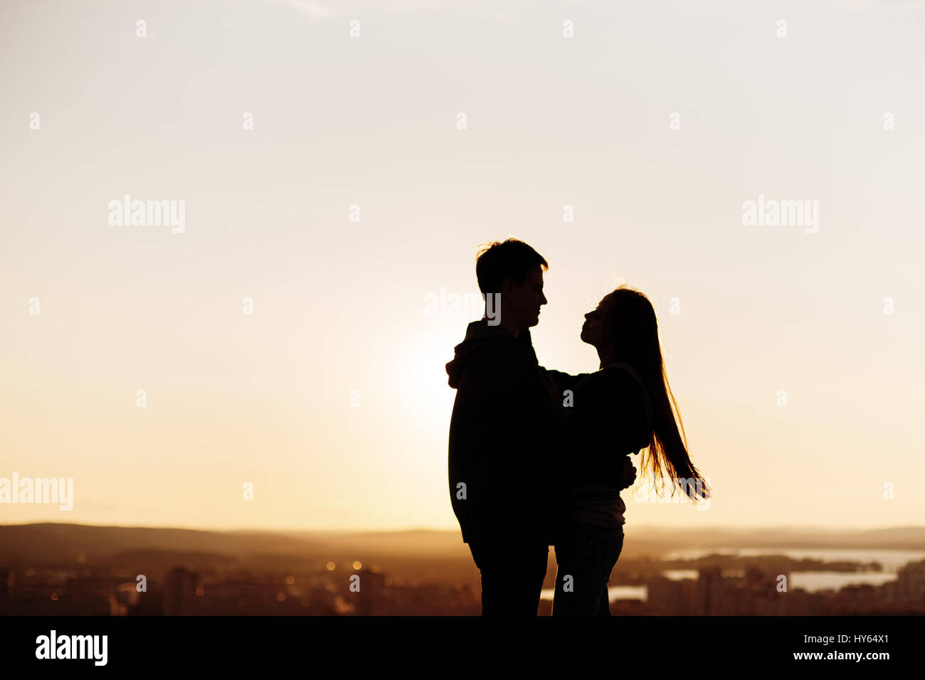 Couple embracing on a roof at the sunset, silhouette Stock Photo