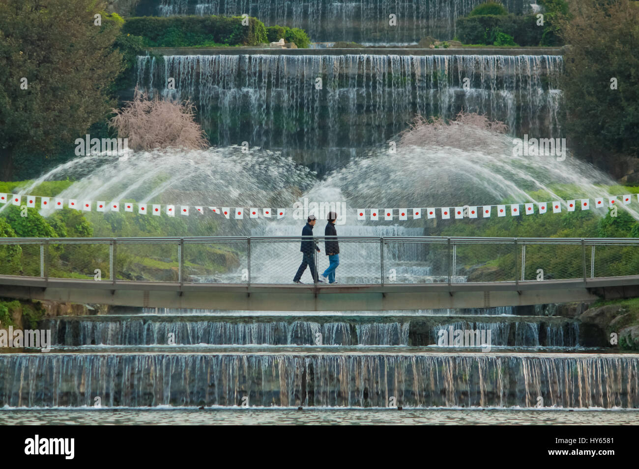 Rome, Italy - April 10, 2011: two unidentified young men walking in Laghetto Eur Park, in front of the main waterfall fountain. This place is also cal Stock Photo