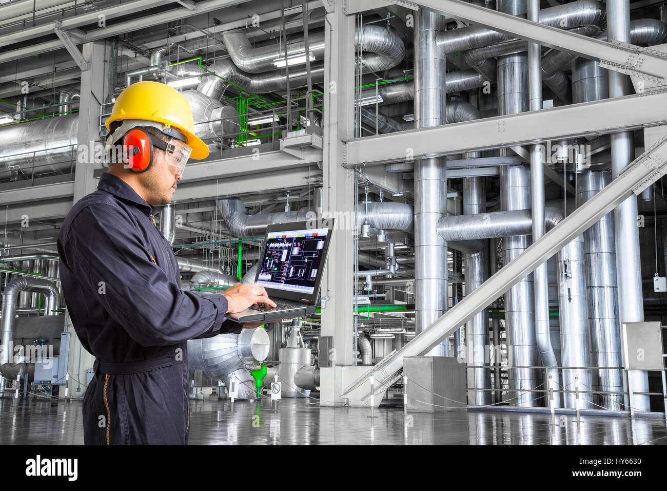 Engineer using laptop computer for maintenance equipment and pipeline system in thermal power plant factory Stock Photo