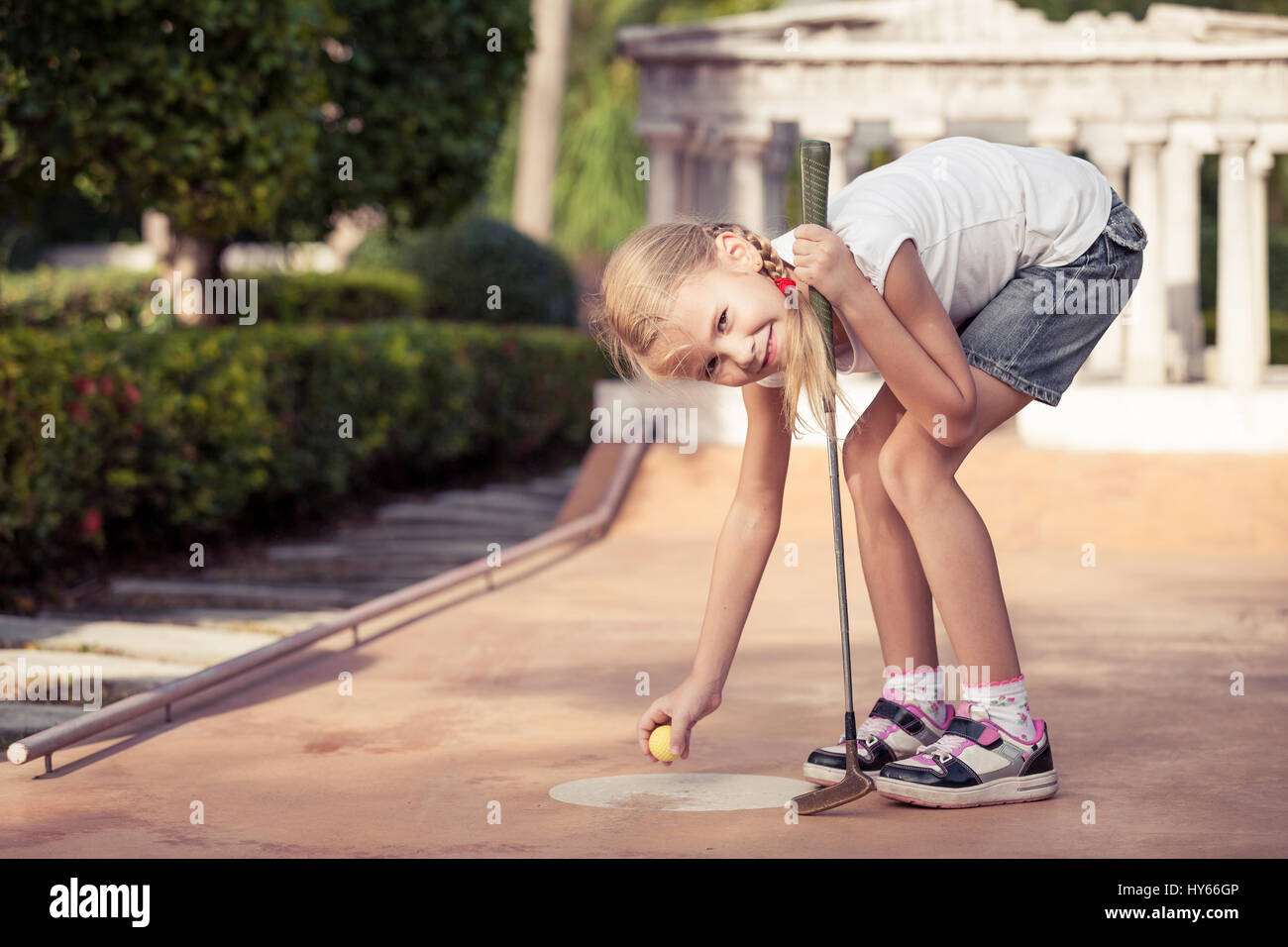 Little girl swinging mini golf club at the day time Stock Photo