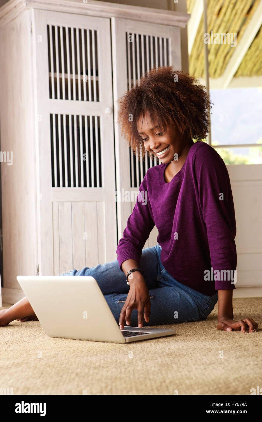 Portrait of a young black woman sitting on floor with laptop Stock ...