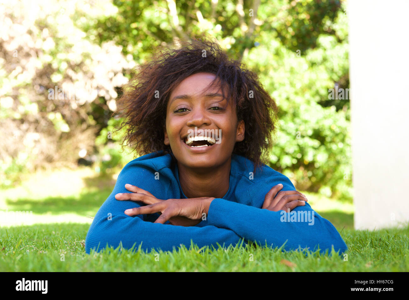 Portrait of an attractive young black woman lying on grass laughing Stock Photo