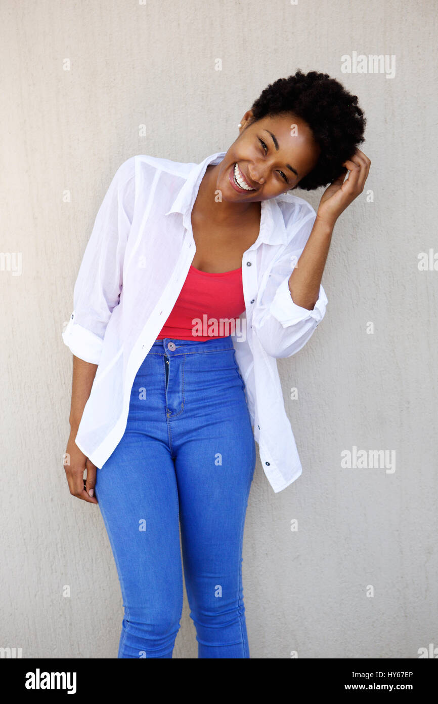 Portrait of a young african woman laughing while standing against a ...