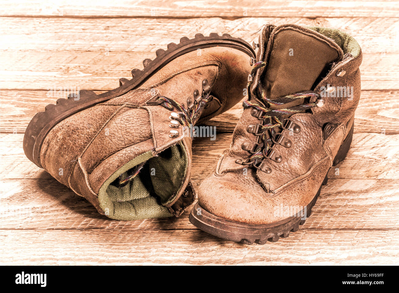 a pair of old, well-worn, hiking boots on weathered wood, retro sepia toning Stock Photo
