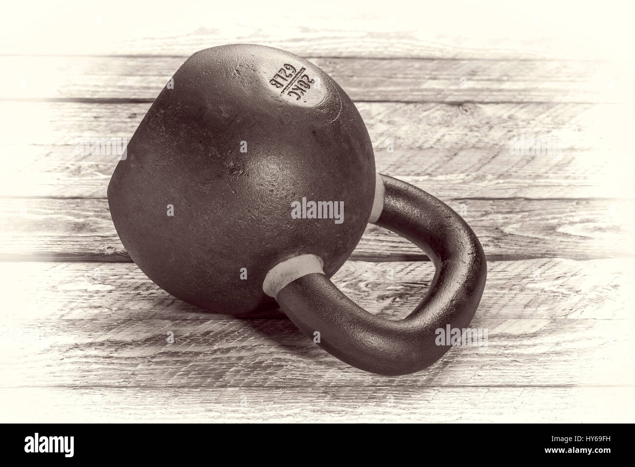 heavy iron kettlebell on a rustic wood background - fitness concept - retro sepia opalotype processing Stock Photo