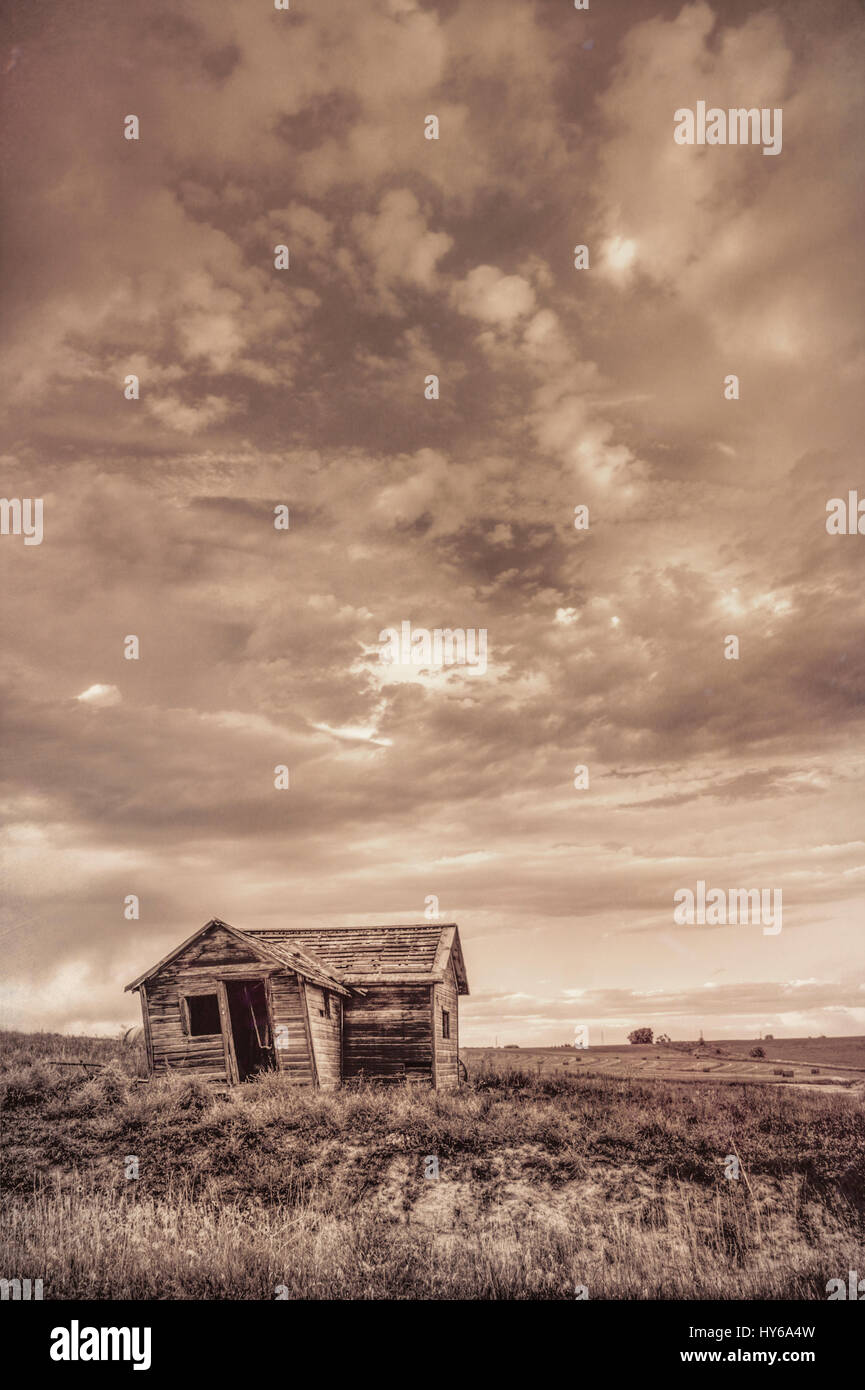 old abandoned farm house on Colorado prairie with stormy sky, sepia toning Stock Photo