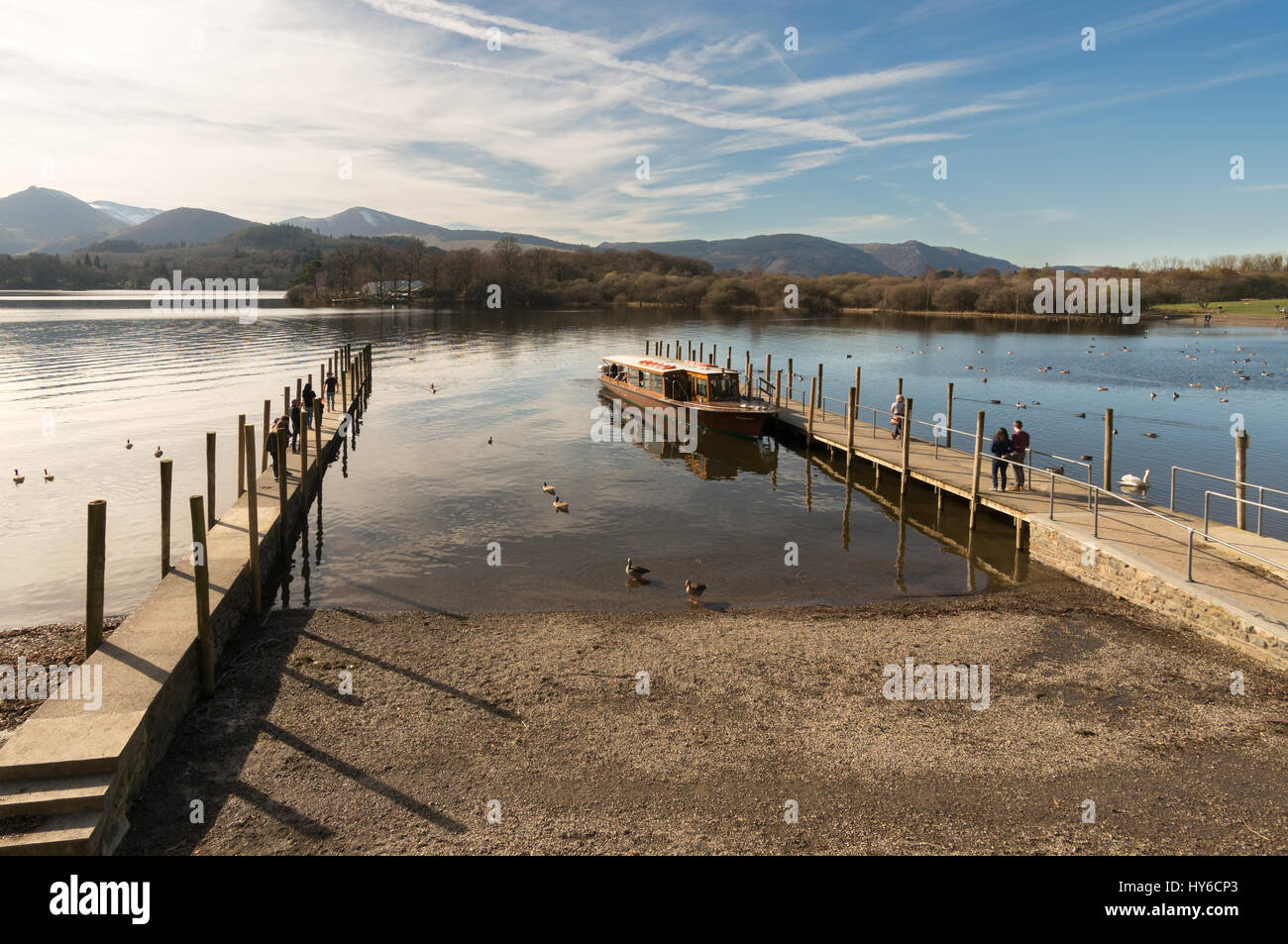 Wide angle view of the jetties on Derwentwater at Keswick with people walking towards a motor launch, Cumbria, England, UK Stock Photo