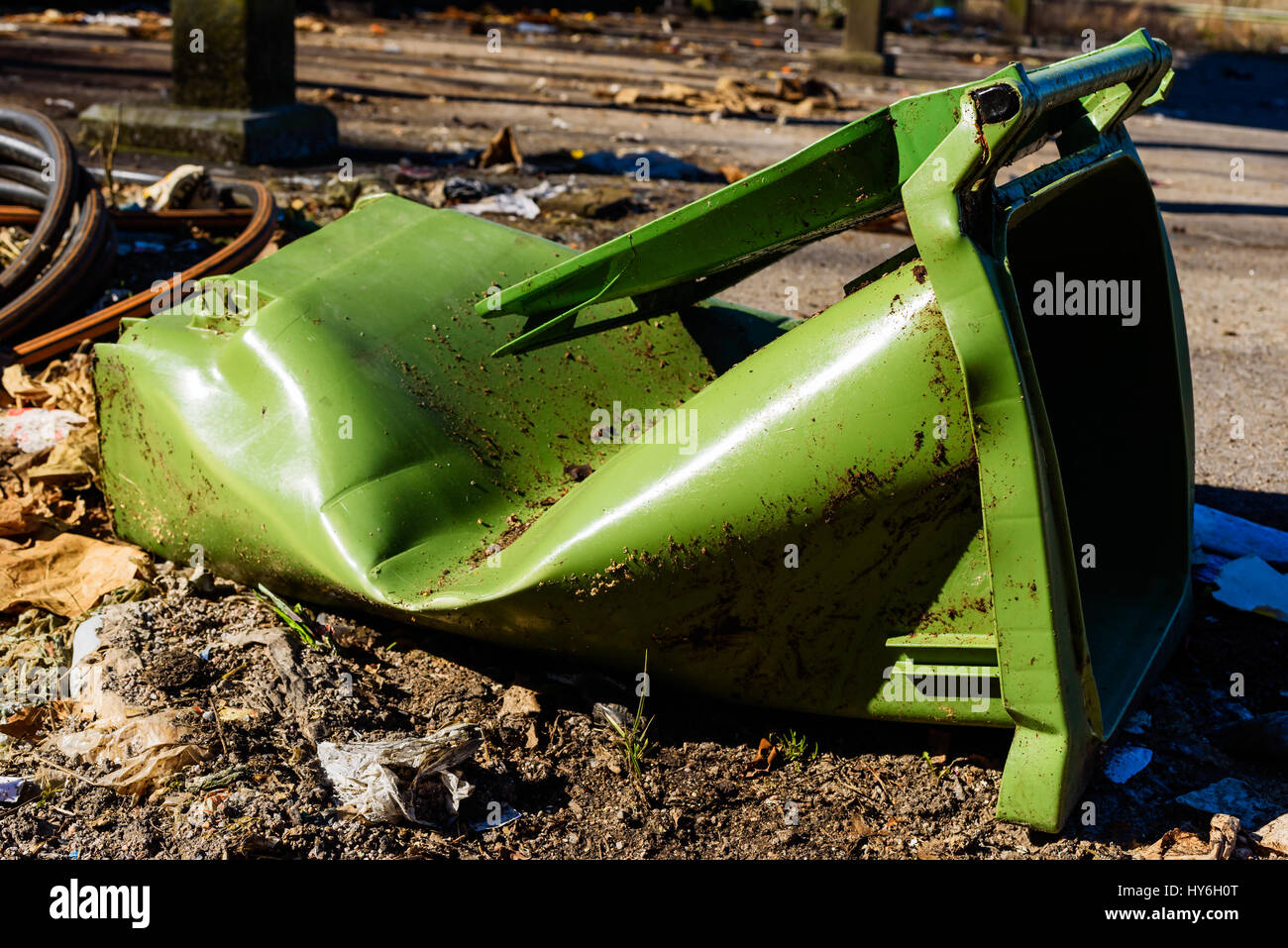 Broken and torn green trashcan lying dirty on the ground. Stock Photo