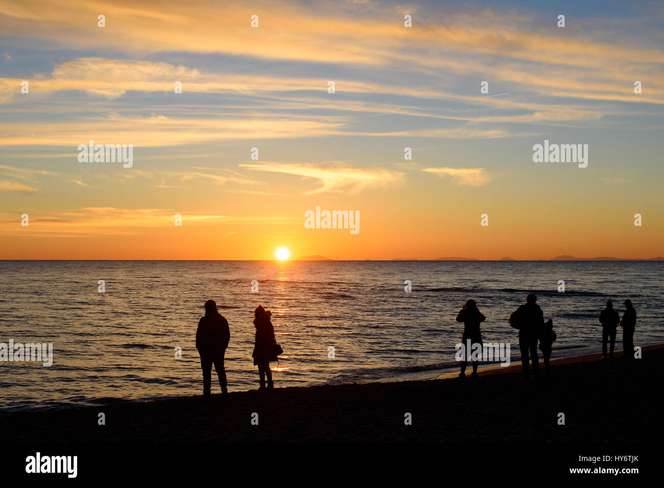 silhouette of people on the beach watching the sunset Stock Photo